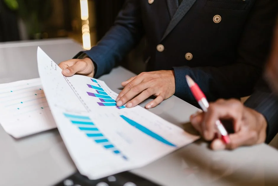 Person analyzes stock data with a smartphone and laptop, indoors.