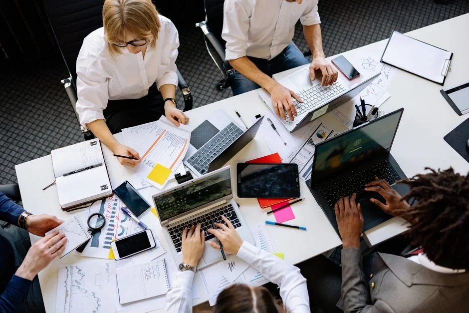 Une équipe variée travaille ensemble sur des stratégies de marketing digital autour d’un bureau, avec des ordinateurs portables et des tablettes.